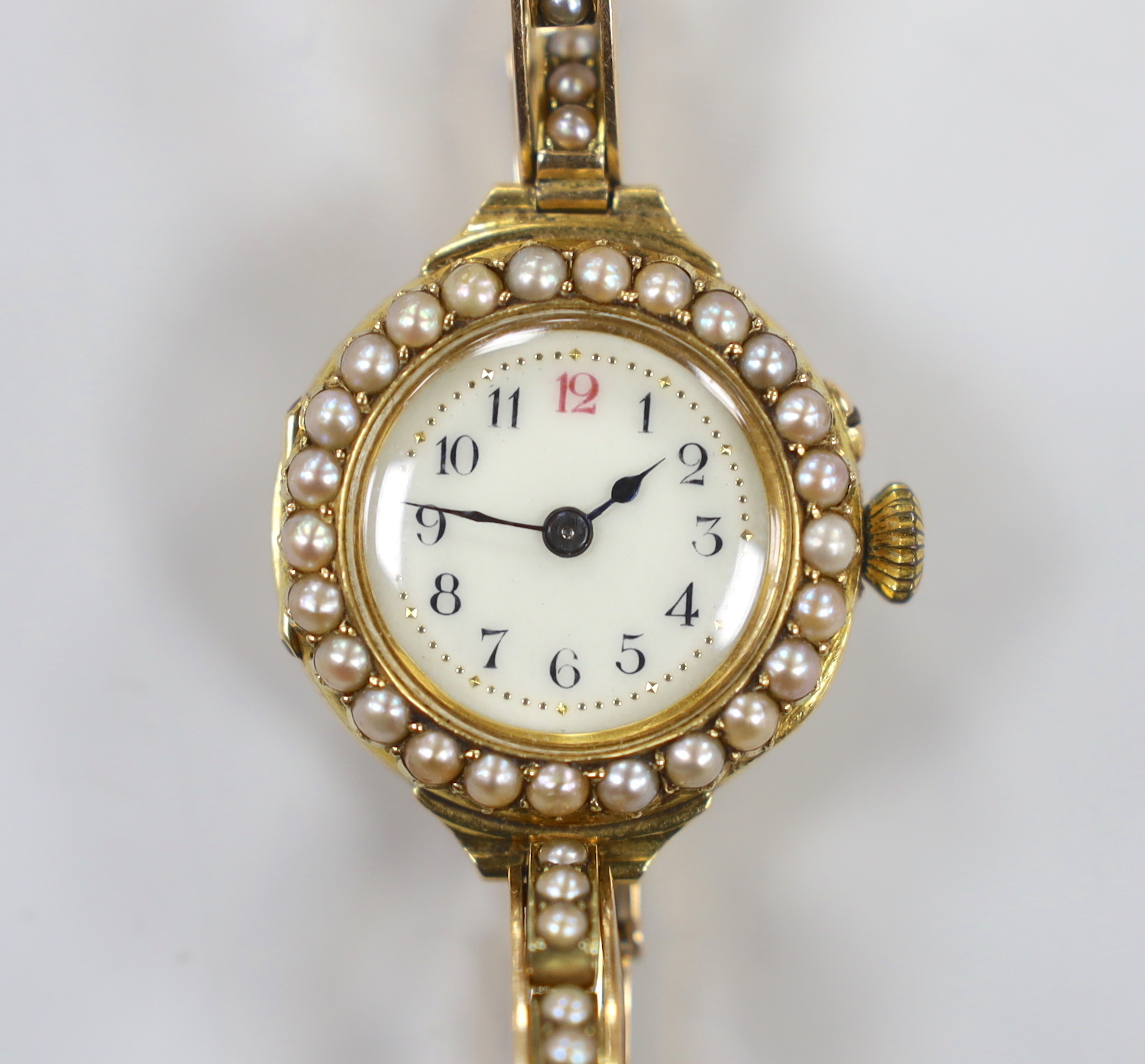 A lady's early 20th century 18ct gold and seed pearl set manual wind wrist watch, on a flexible 15ct and seed pearl set bracelet